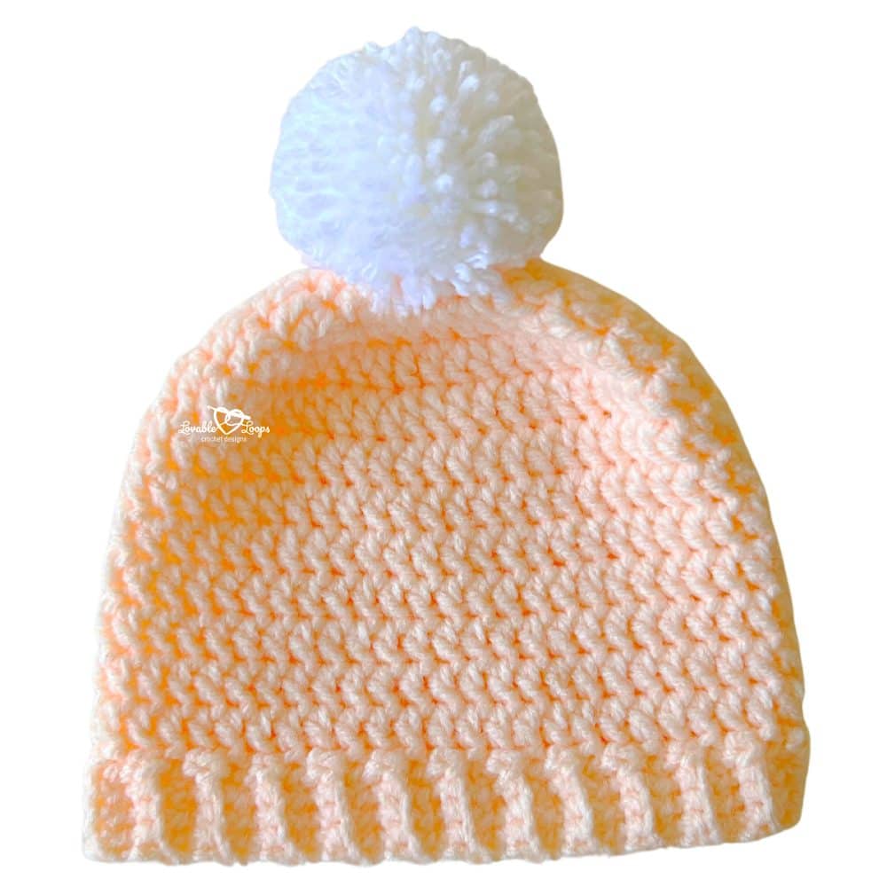 Finished crochet toddler hat pattern made with bulky yarn, featuring a ribbed brim and white pom pom