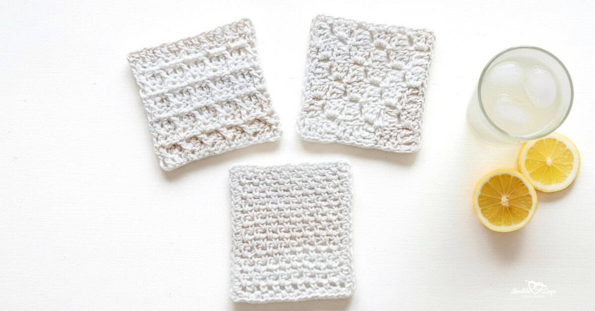 Top-down photo of three beginner crochet coasters on a whitewashed table, including two textured cream square coasters and one simple cream crochet coaster beside a glass of lemonade and lemon slices.
