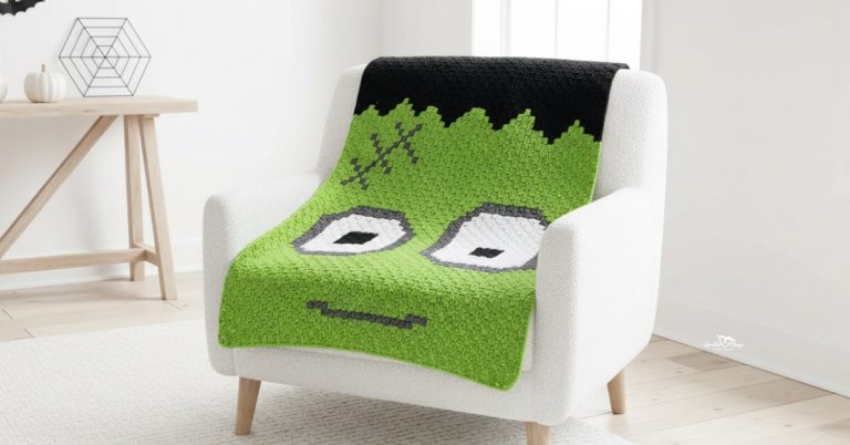 Frankenstein crochet blanket draped over a white armchair in a bright Halloween-themed room with light wood floors and simple spooky decor.