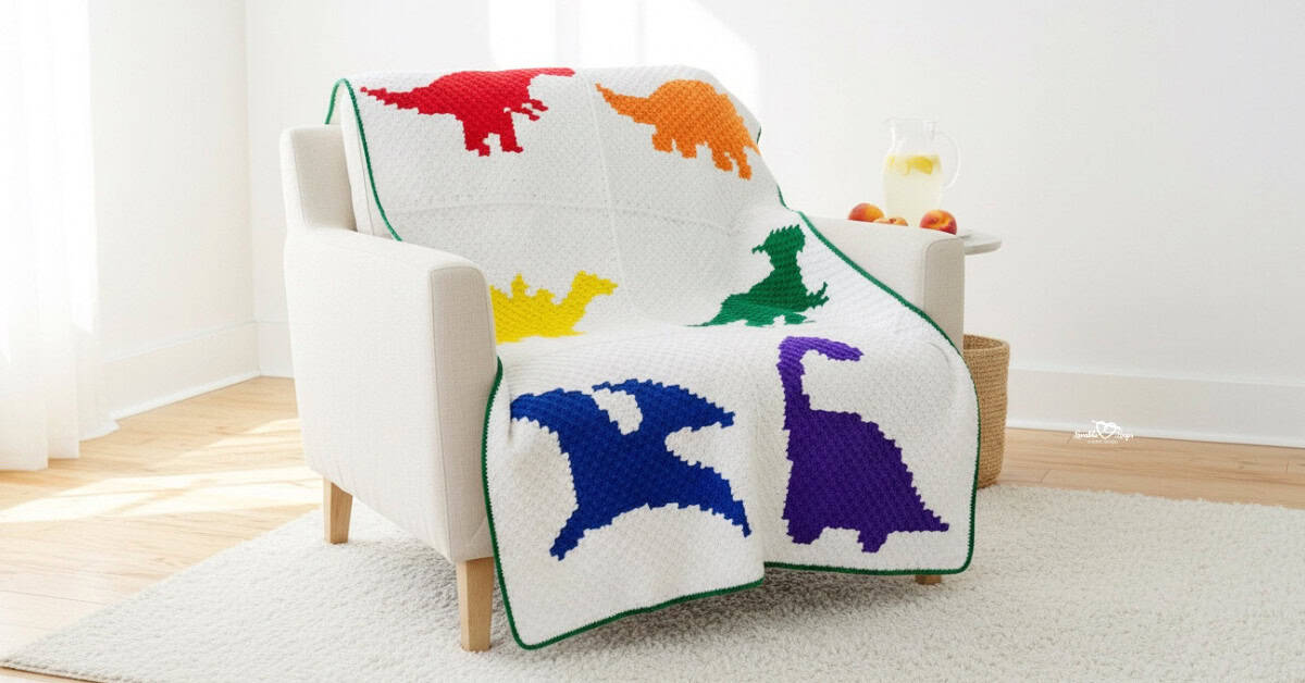 White crochet heart blanket draped over a cream armchair in a bright living room, featuring colorful rainbow hearts along the edges, with a side table holding lemonade and fruit and a woven basket nearby.