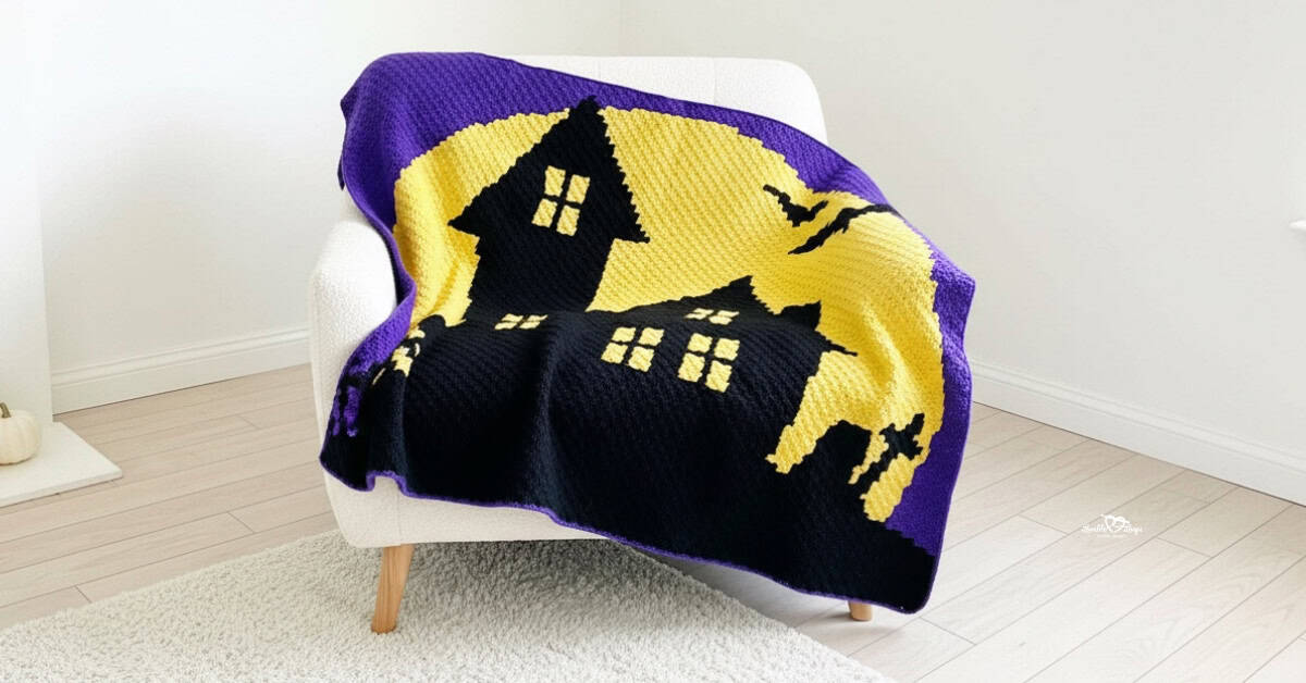 Haunted house crochet blanket draped over a white armchair in a bright room with light wood floors and a soft white rug.