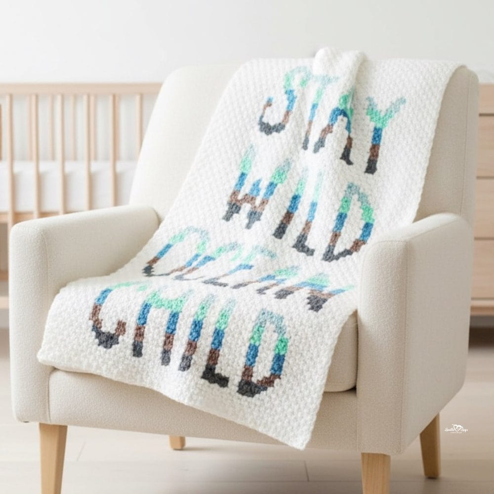 C2C word crochet blanket draped over a cream armchair with the phrase &ldquo;Stay wild ocean child&rdquo; and arrow motifs.