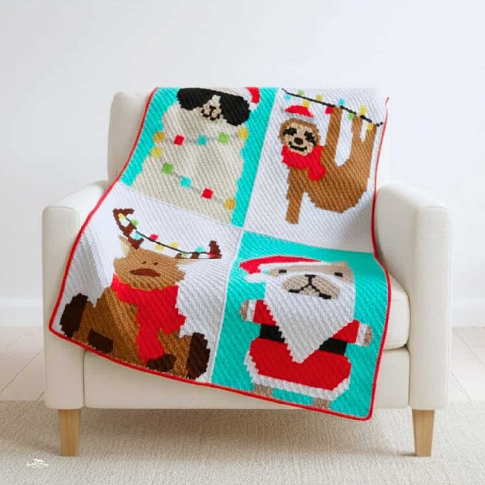 Christmas crochet blanket draped over a cream armchair in a bright room, featuring festive animal blocks with a snowman, sloth, reindeer, and Santa design.