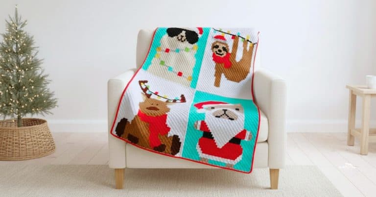 C2C crochet Christmas blanket with festive animal squares featuring a dog snowman, sloth, moose, and Santa draped over a white armchair in a bright living room with a small lit Christmas tree.