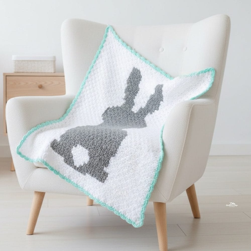 C2C bunny crochet blanket draped over a cream armchair, featuring a gray bunny silhouette on a white background with a mint border.