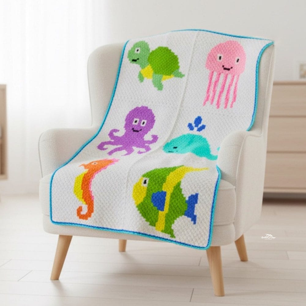 C2C sea animal crochet blanket draped over a cream armchair, featuring a turtle, jellyfish, octopus, whale, seahorse, and tropical fish.