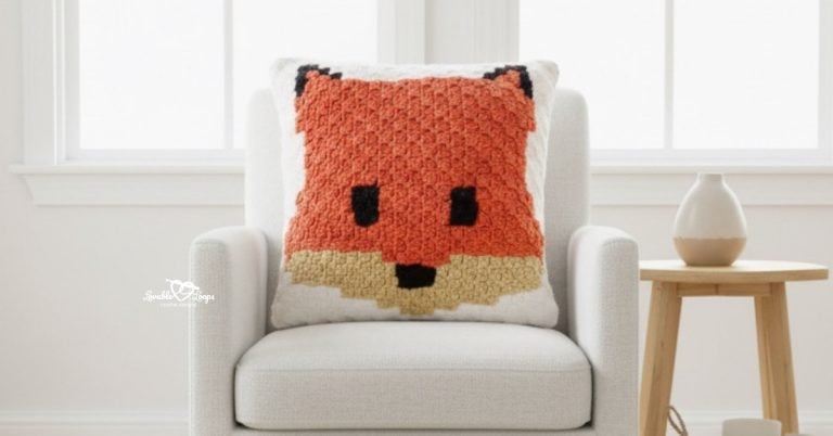 Fox face crochet pillow displayed on a white armchair beside a light wood side table.