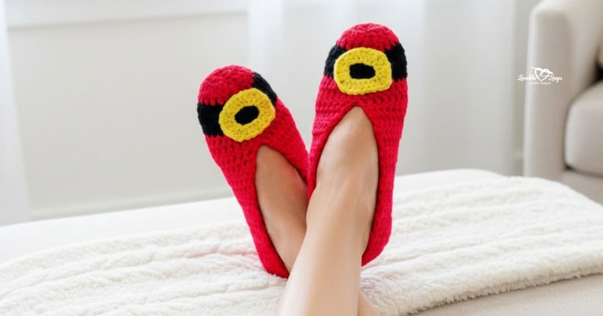 Woman relaxing with her feet up on a soft white blanket, wearing red crochet Santa slippers with black and yellow belt buckle details.