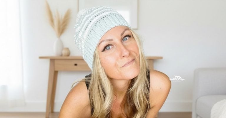 Woman wearing a light blue crochet slouchy beanie, photographed in a bright neutral living room with soft natural light.