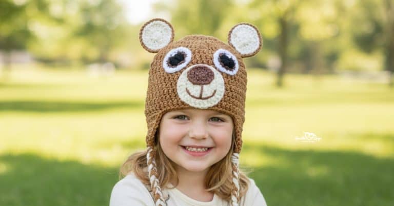 Child wearing a brown crochet bear hat with braids in a bright sunny park with green grass and softly blurred trees in the background