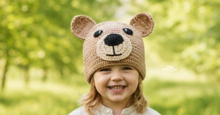 Child wearing a brown crochet bear hat on a sunny green nature trail with softly blurred trees in the background