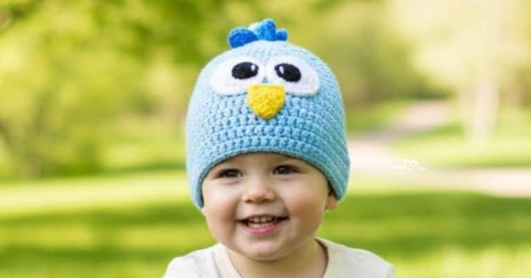 Child wearing a blue crochet bird hat on a bright green nature trail with soft trees in the background