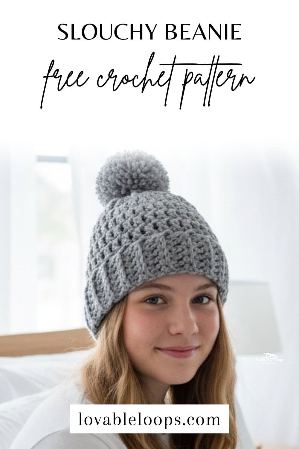 Slouchy beanie free crochet pattern Pinterest pin with black text above a photo of a model wearing a gray crochet pom pom beanie in a bright neutral bedroom.