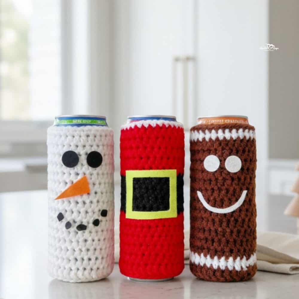 Crochet Christmas can cozies displayed on a bright kitchen island, including a white snowman, red Santa, and brown gingerbread design with soft neutral holiday styling.