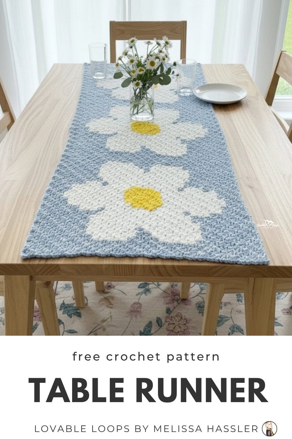 Crochet daisy table runner pattern shown on a light wood dining table with three white daisy flowers on a soft blue background.