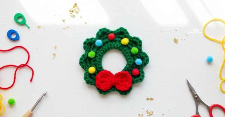Crochet wreath applique centered on a white desktop with red and yellow yarn, scissors, a crochet hook, colorful stitch markers, and festive gold accents around it.