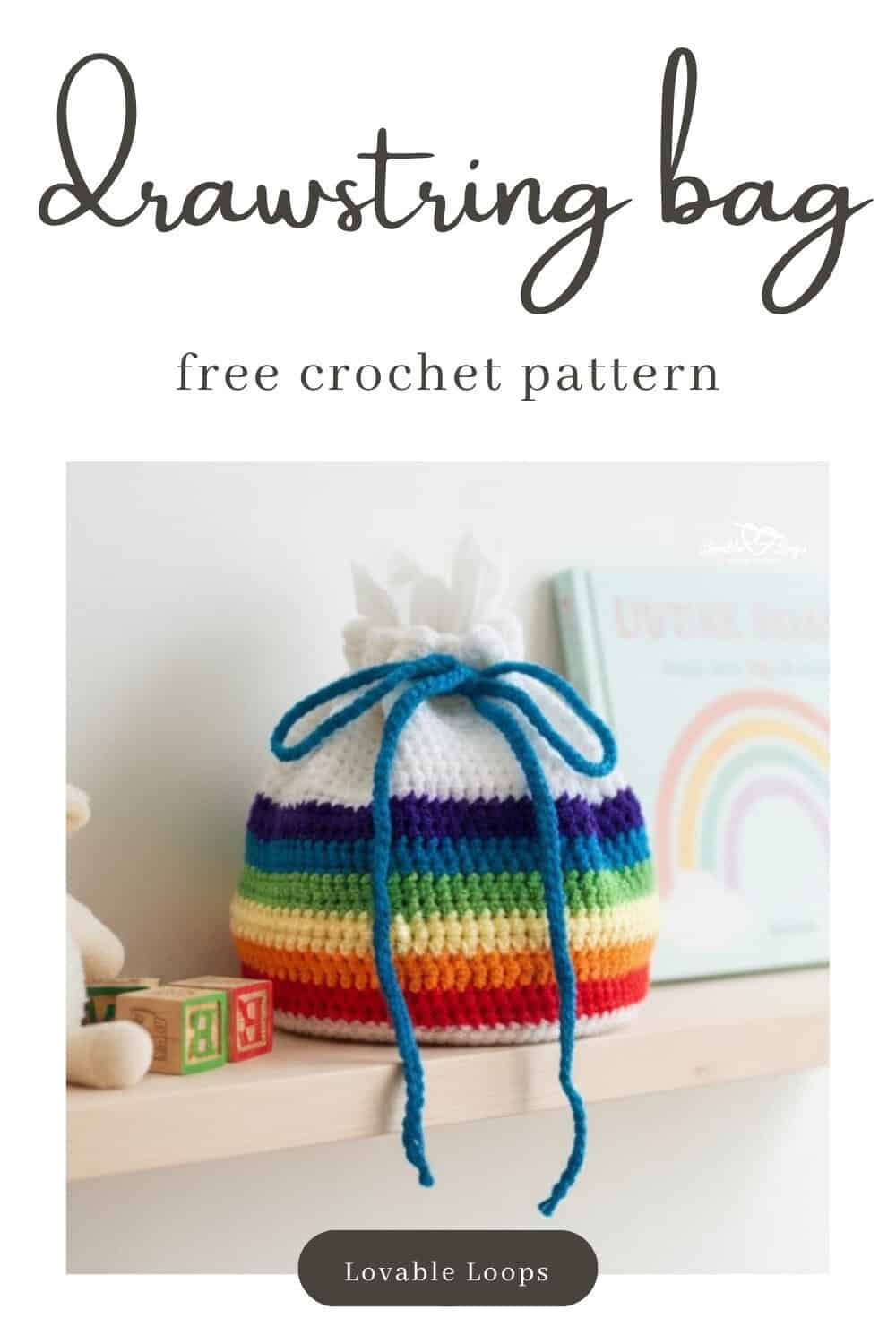 Rainbow crochet drawstring bag sitting on a light wood shelf in a bright kids room, styled with tissue paper inside, a plush lamb, toy blocks, and pastel rainbow wall art.