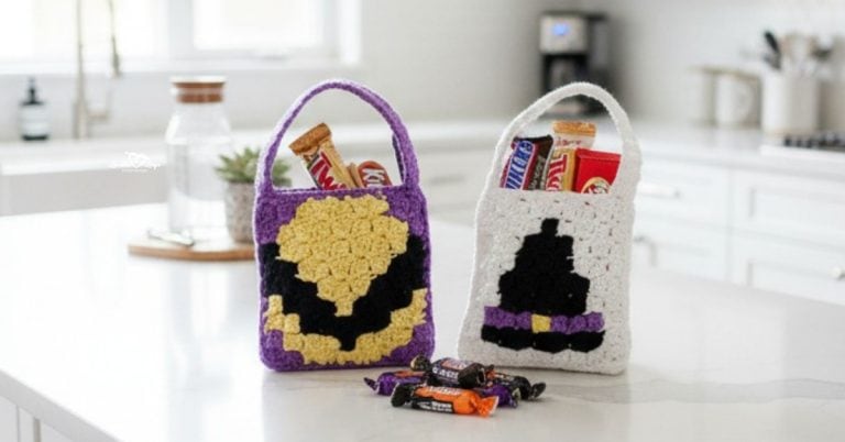 Two mini reversible crochet Halloween treat bags on a bright white kitchen island, one purple with a candy corn design and one white with a black witch hat, both filled with candy.