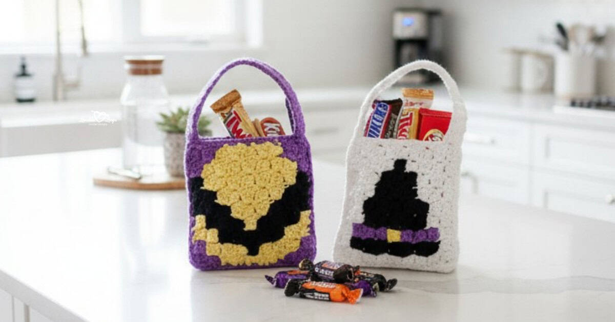 Two mini reversible crochet Halloween treat bags on a bright white kitchen island, one purple with a candy corn design and one white with a black witch hat, both filled with candy.