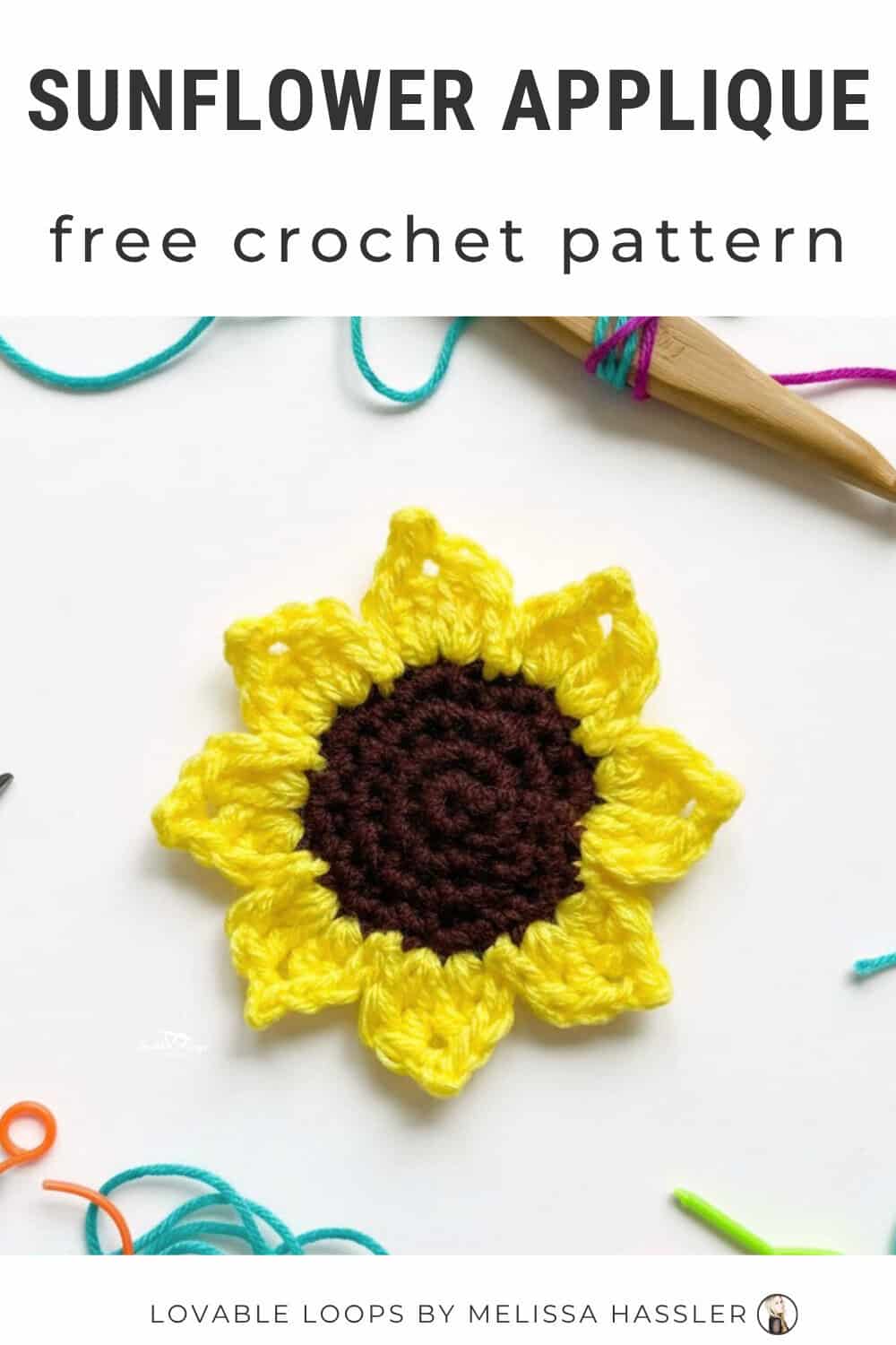 Crochet sunflower applique pattern with bright yellow petals and a dark brown center on a white desktop with yarn and crochet tools nearby.