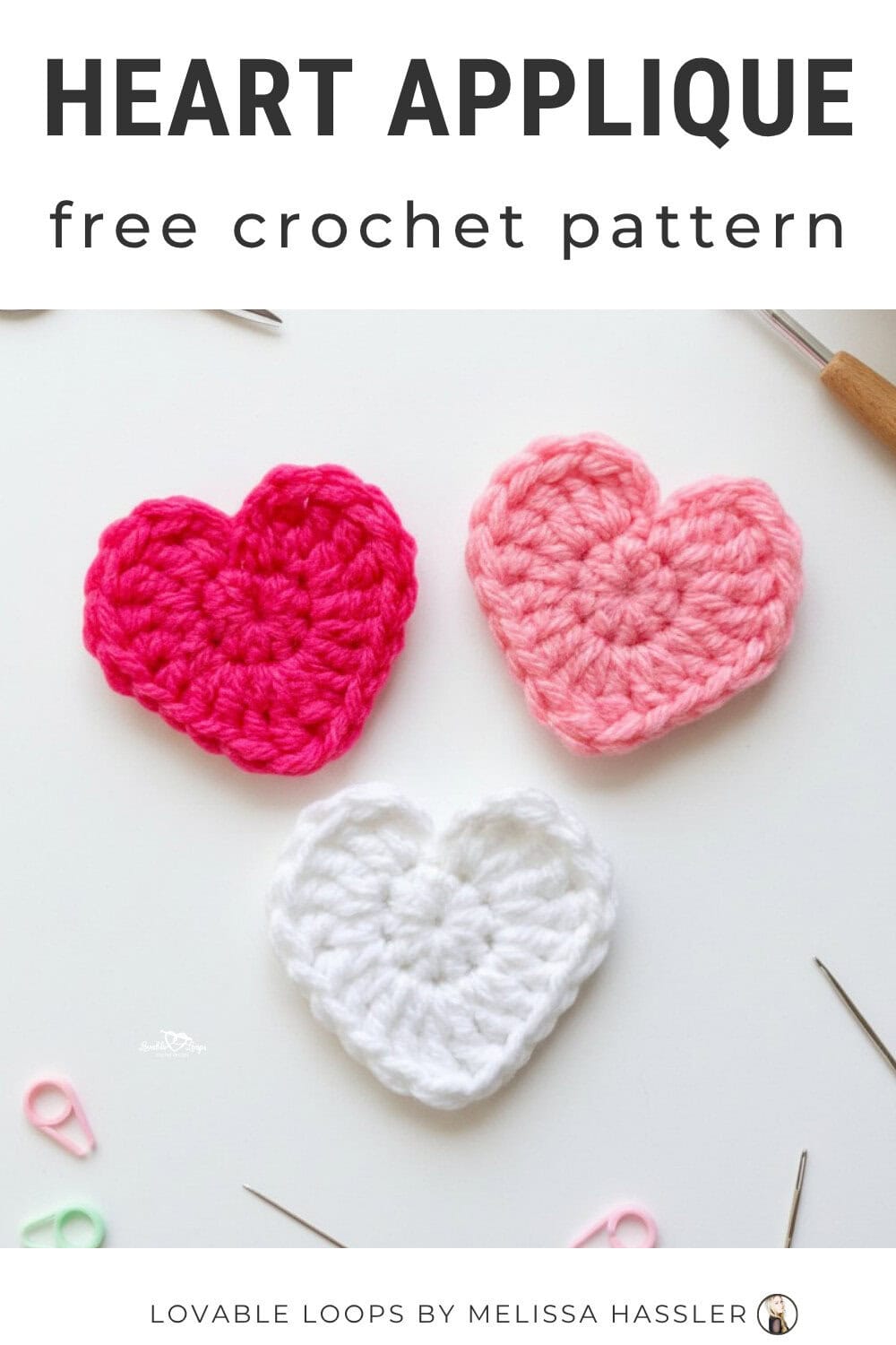 Heart applique crochet pattern displayed on a bright white desktop with three colorful crochet hearts and simple craft tools around them.