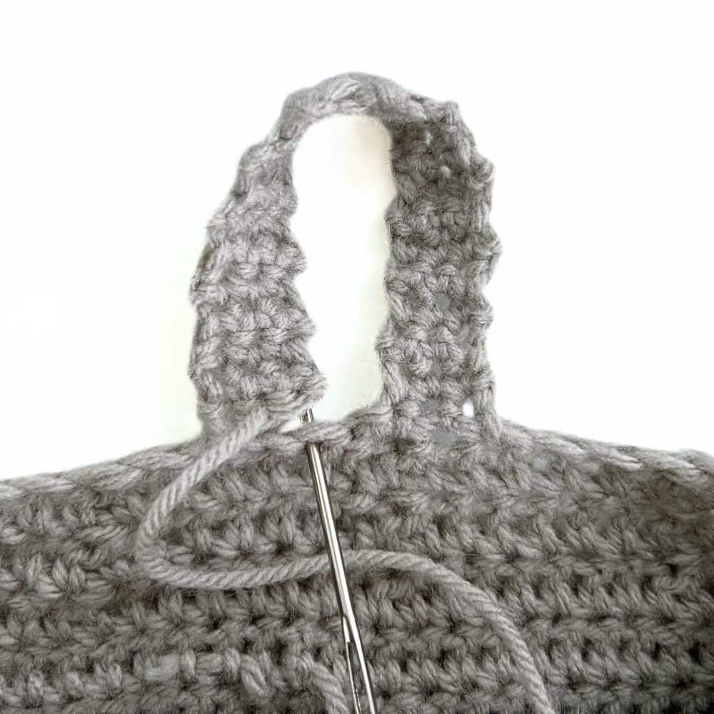 Close-up of the crochet hanging basket loop being sewn onto the basket with a yarn needle.