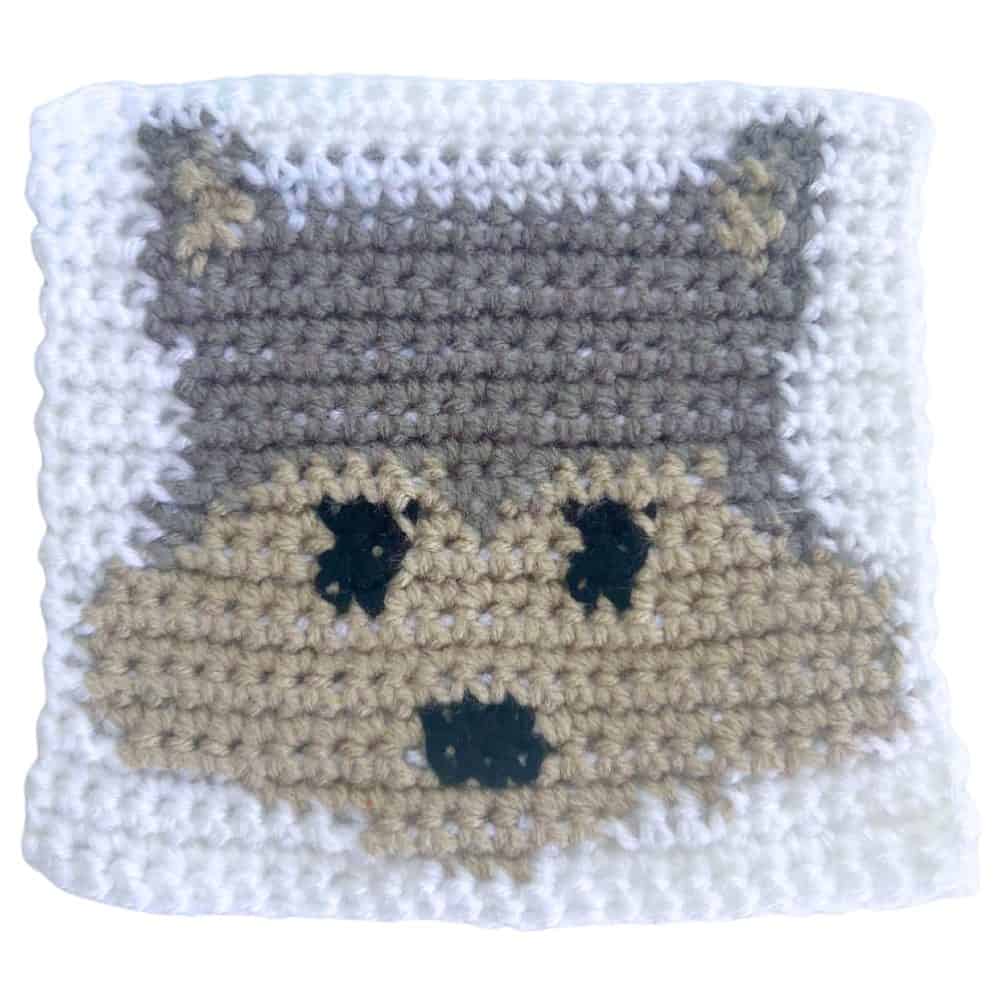 Handmade wolf crochet square worked in rows of single crochet stitches with gray, dark gray, tan, black, and white yarn.
