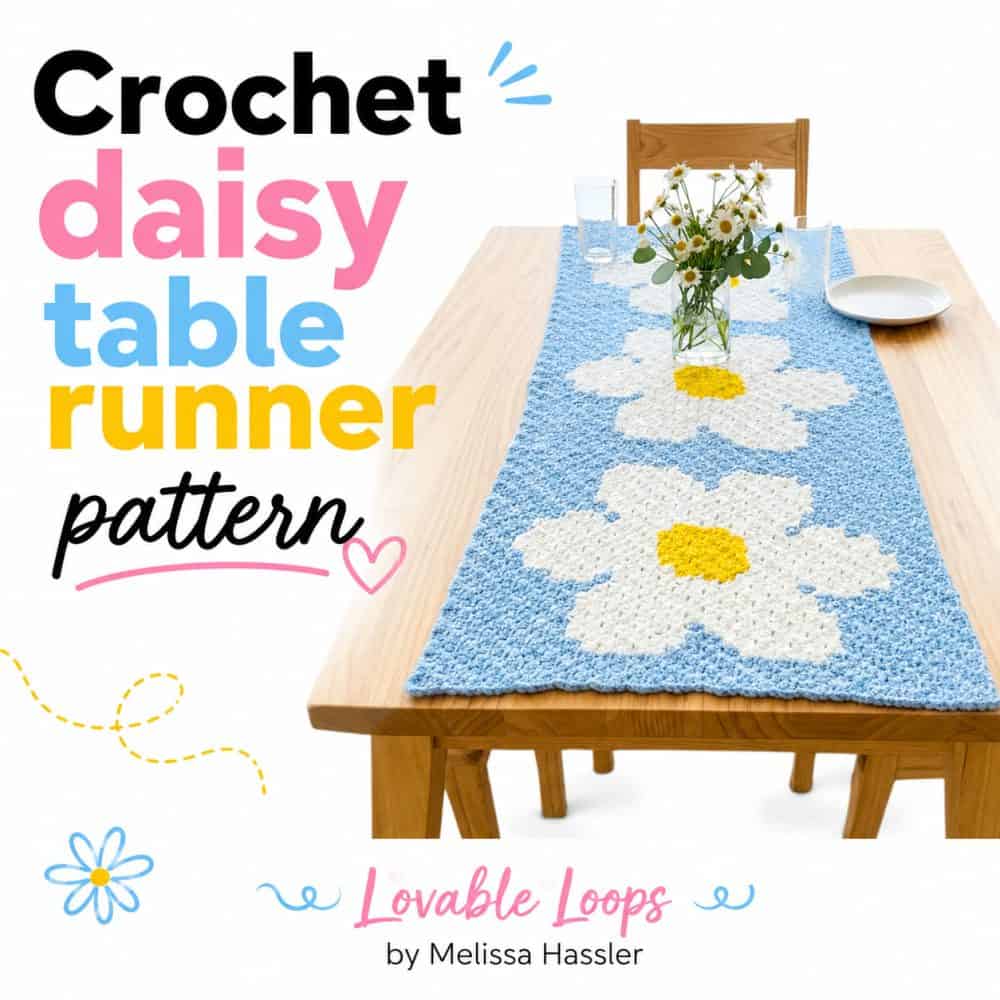 Handmade blue crochet table runner featuring large white daisy motifs with yellow centers, displayed on a wooden dining table with spring floral decor and Crochet Daisy Table Runner Pattern text.