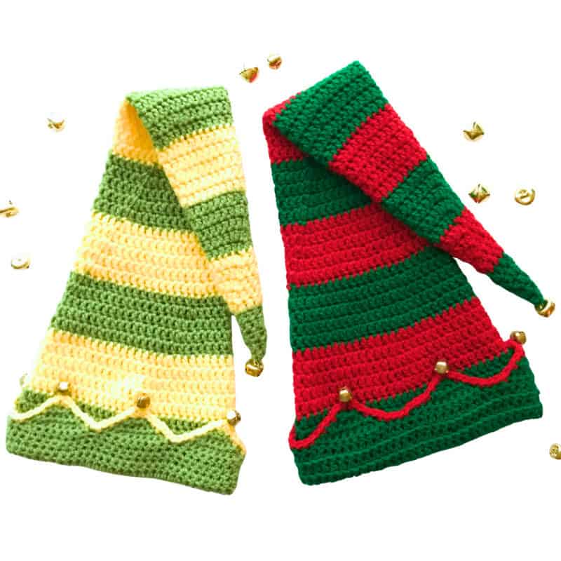 Two striped crochet elf hats with long pointed tops and peaked brims, decorated with small gold jingle bells on a white background.