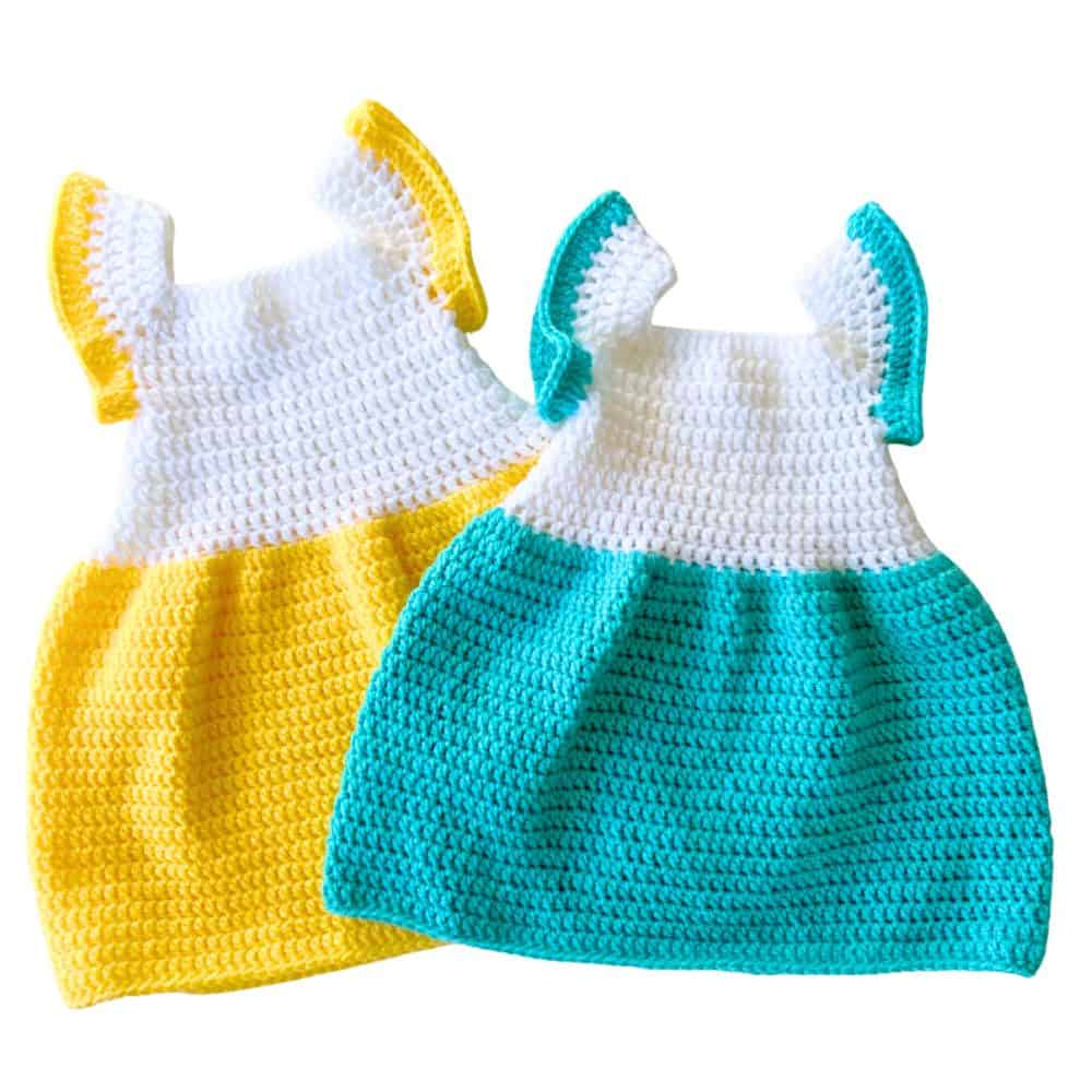 Two finished crochet baby dresses with white bodices and full skirts, one yellow and one turquoise, with matching sleeve trim.