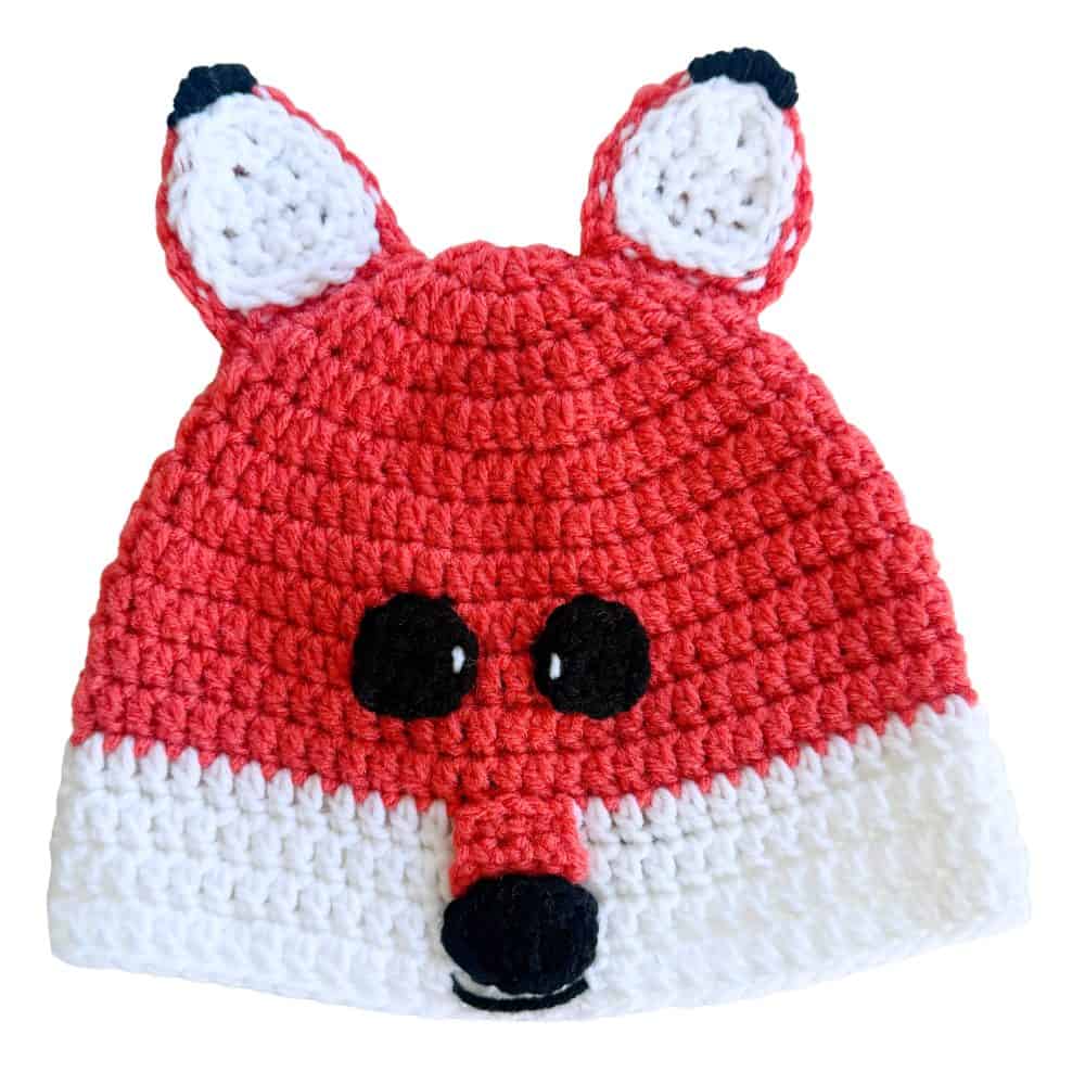 Finished orange and white crochet fox hat with pointed ears, black ear tips, black eyes and nose, a long snout, and a small stitched smile.